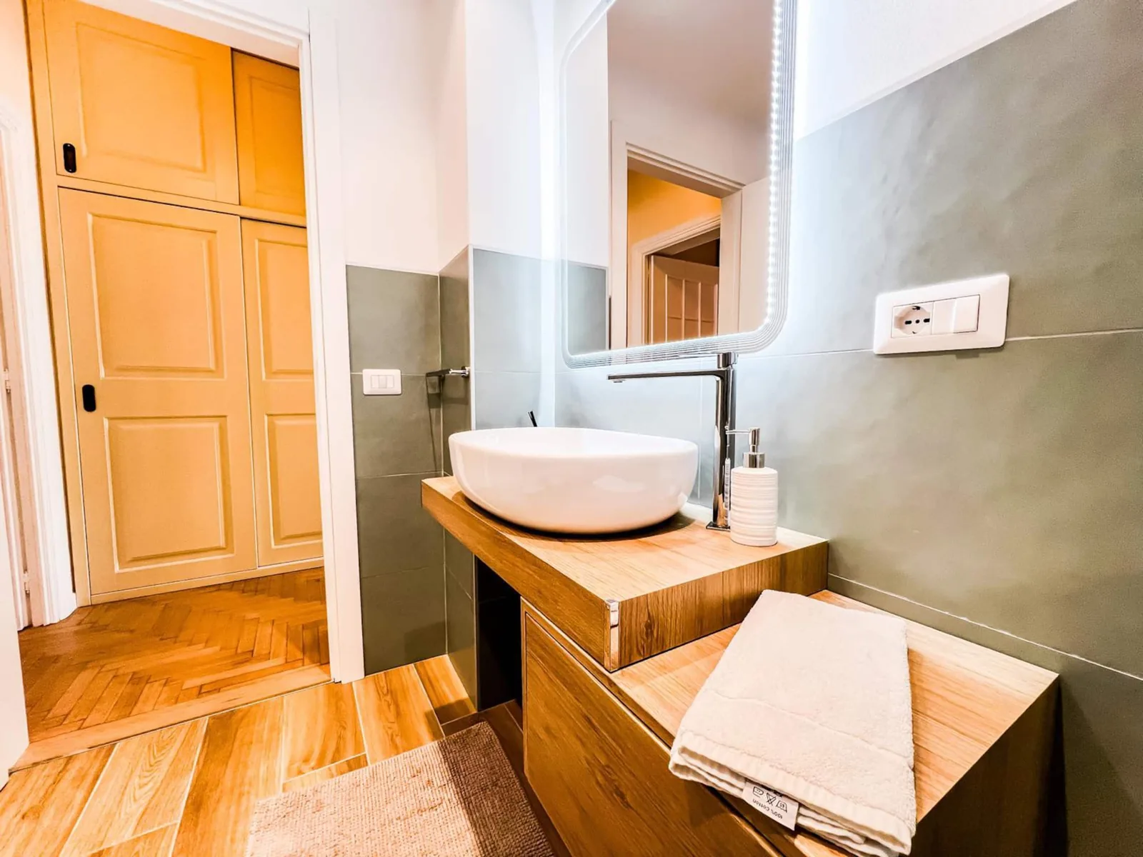 Lavabo d'appoggio, specchio e asciugamani puliti nel bagno dalle pareti verde chiaro