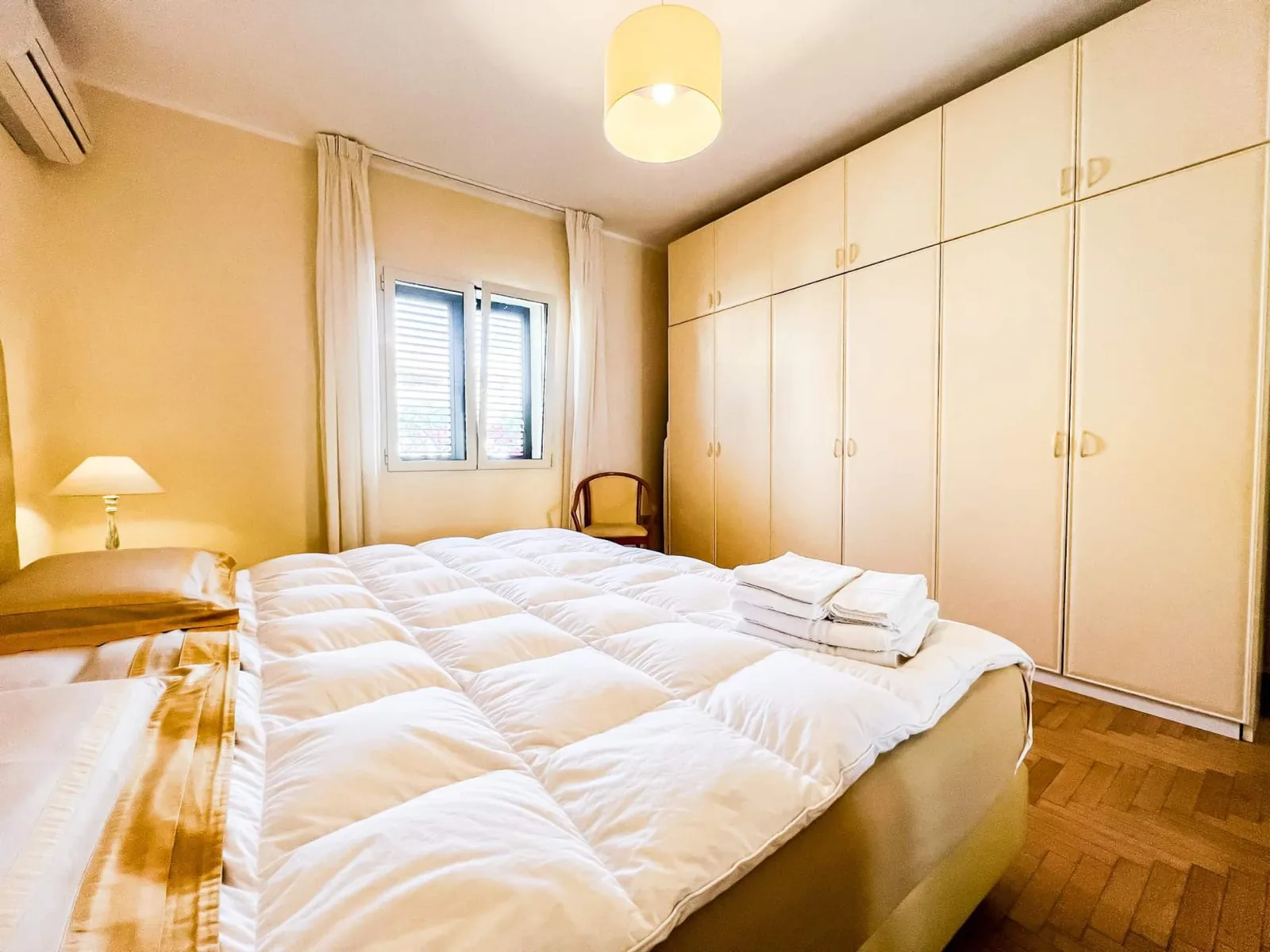 Letto matrimoniale con asciugamani piegati, armadi a muro e finestra della camera