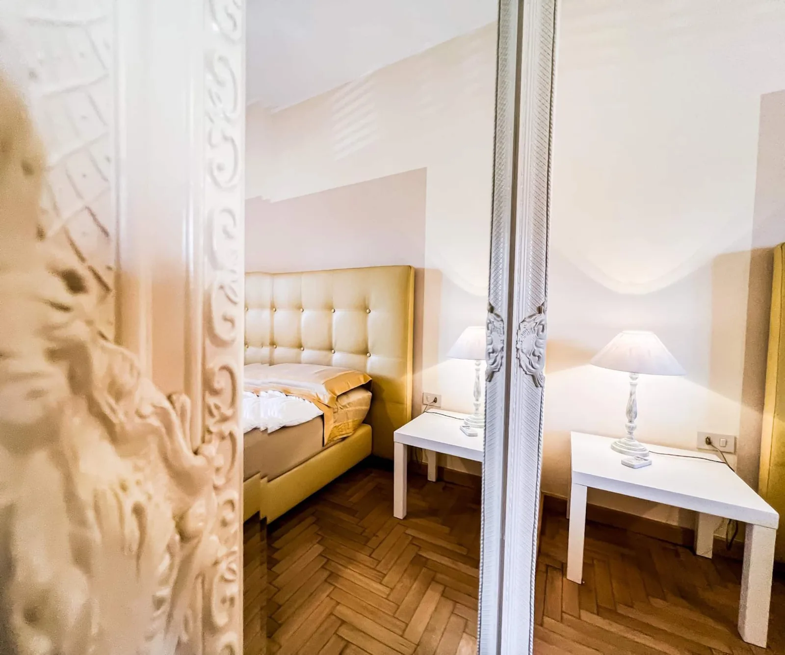 La camera matrimoniale riflessa nello specchio decorato accanto alla porta