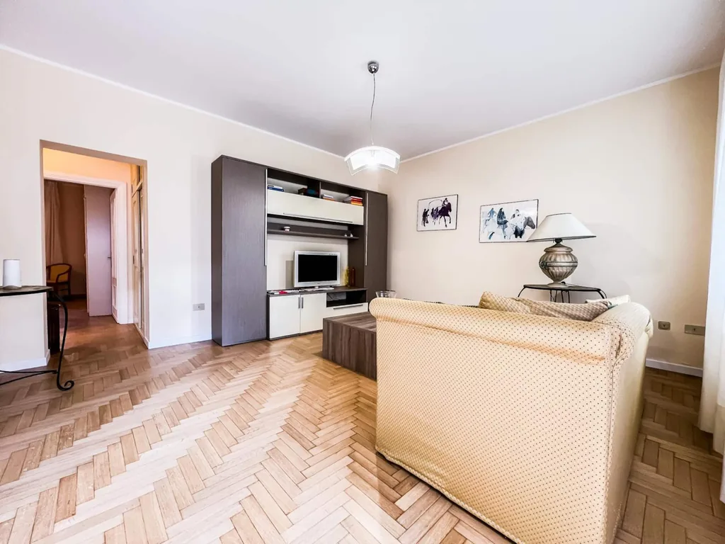 Il divano del soggiorno visto dall'ingresso, con il mobile scuro e il passaggio interno