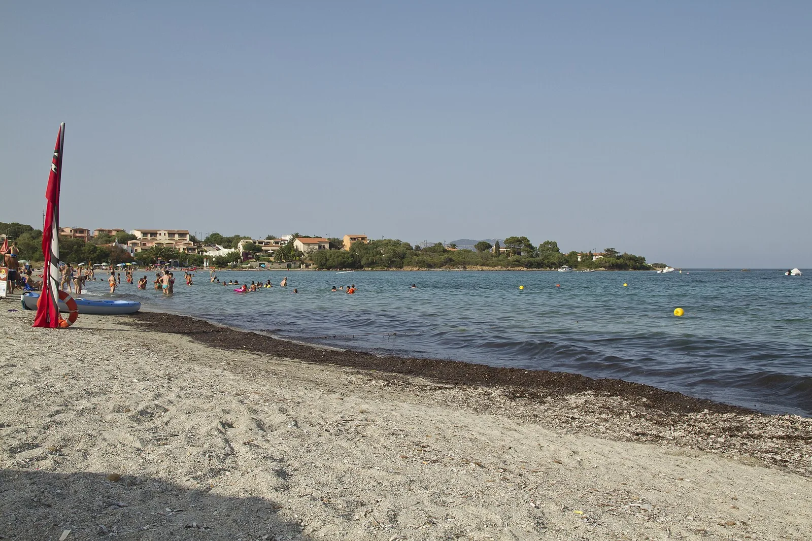 La spiaggia di Pittulongu con l'acqua bassa e turchese e le case affacciate sulla costa