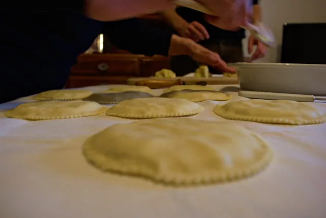 Seadas crude appena chiuse, allineate su una tovaglia bianca durante la preparazione in cucina di casa