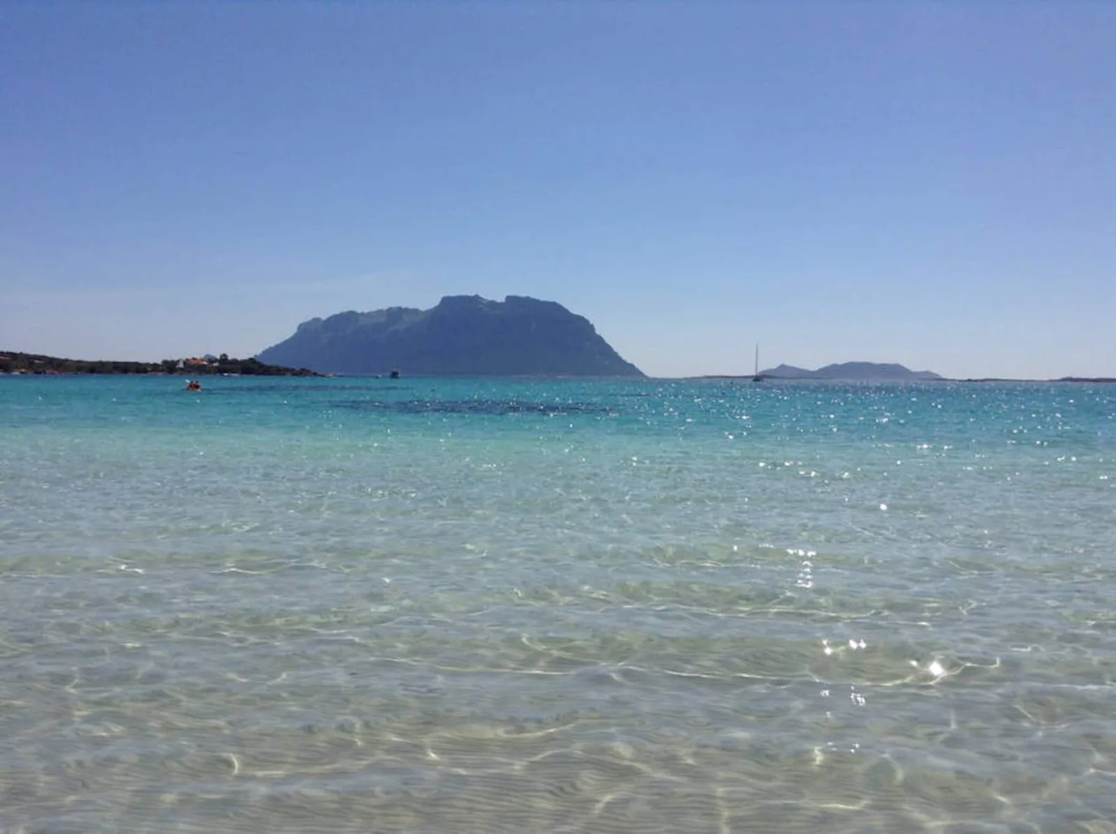 Acqua bassa e trasparente con il profilo dell'isola di Tavolara all'orizzonte